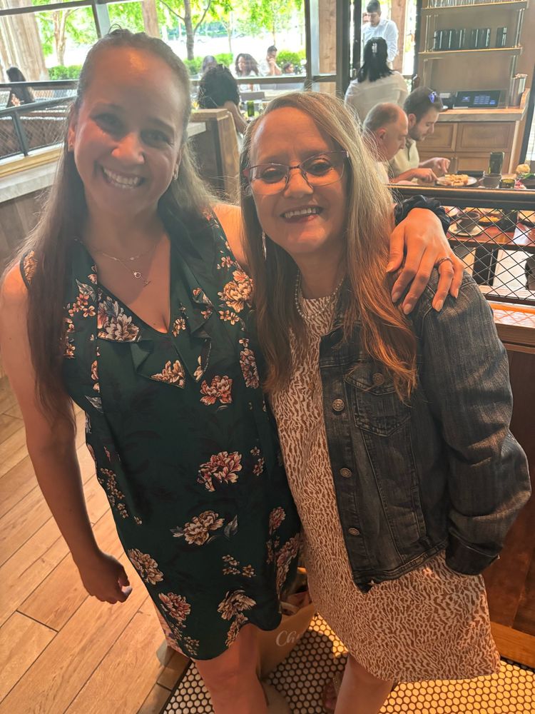 Daughter and mother. Daughter is much larger than mother and looks like she ate her mom. Both smile in restaurant in Mothers Day