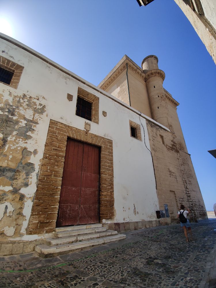 Cadiz old cathedral looks like a cross between a castle and a rustic farmhouse. The entrance is a large red door surrounded by brick. The section of the building facing the sea has no windows but has a small turret.

Why? The English burnt down the original building during one of many attacks on the city. So the first cathedral was rebuilt to look drab so it was less likely to be attacked in the future!