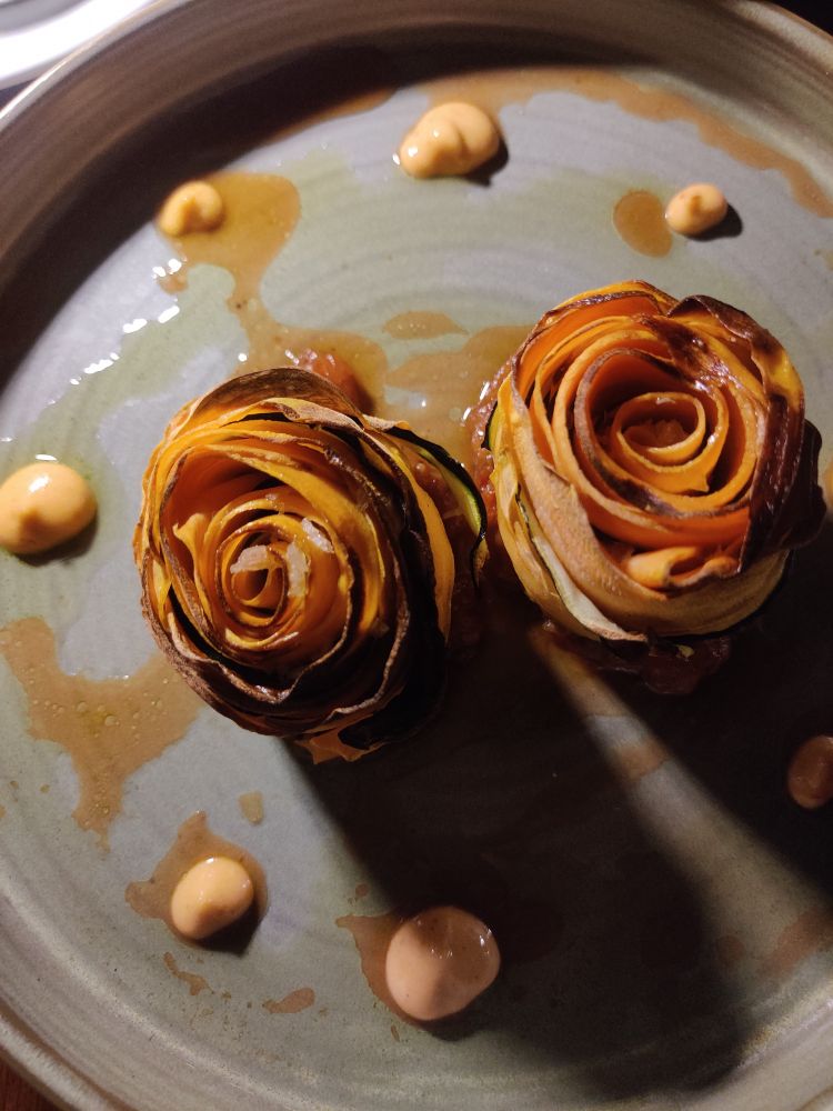 Thin slices of courgette and sweet potato wrapped into what looks like baked roses