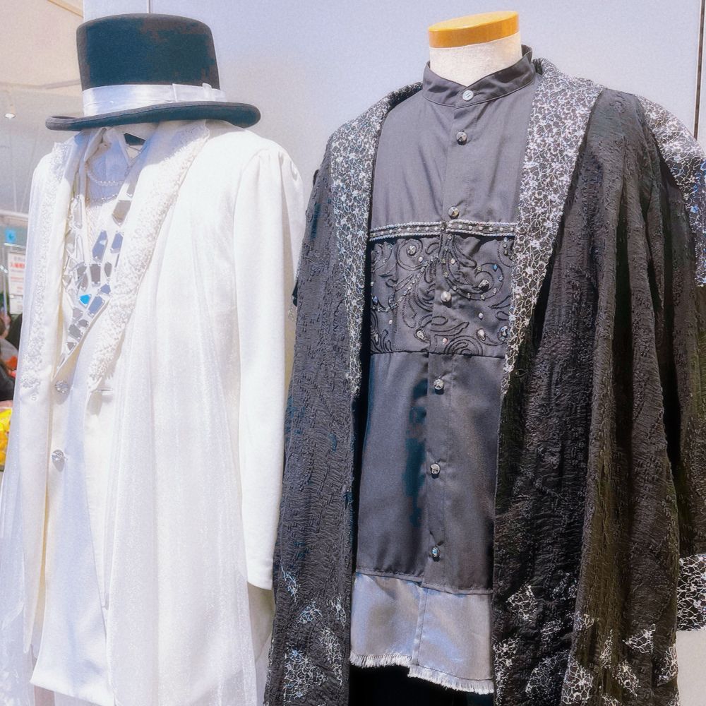 『ひろしとハレヨンくんのぽっぷあっぷすとあ』の展示品。ソロライブツアーmessengerにて神谷さんが着用していた衣装2着の写真。向かって左側が白いスーツ、右側が黒のセットアップ。