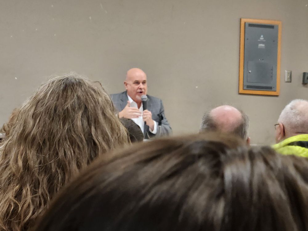 Congressman Mark Pocan (D-WI), a bald white man wearing a grey suit and white shirt, talks to constituents about the nightmare that's upon us