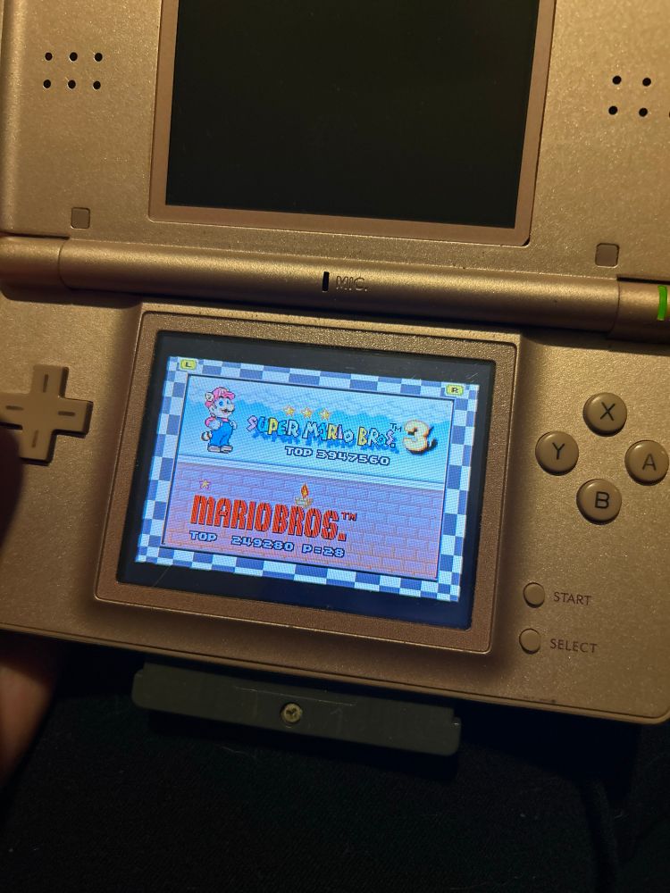 Nintendo DS lite displaying the title screen of the Super Mario Bros. 3/Mario Bros. (TM) game boy cartridge