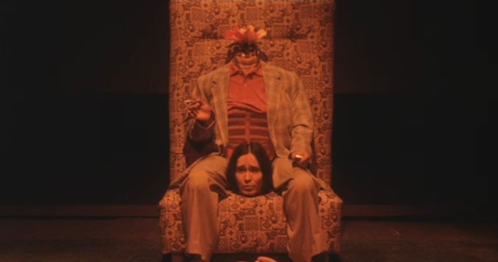 Talking Head
A man in a suit sits on a chair facing the camera, his head in his lap