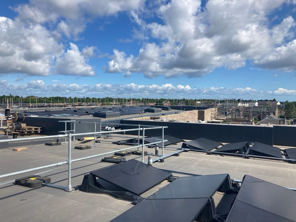 View from roof of development of extra care housing on Polton St, Bonnyrigg which is under construction, showing solar array with hills and blue sky in distance. 