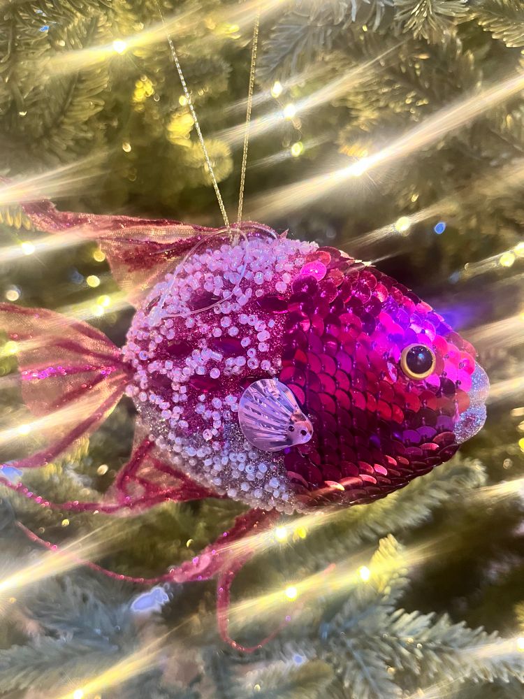 A hot pink fish ornament hanging on a tree