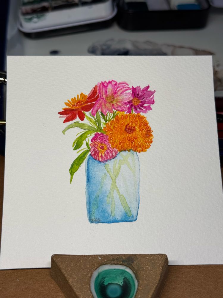 Photo of a watercolor painting of five brightly colored dahlias in a blue jar 