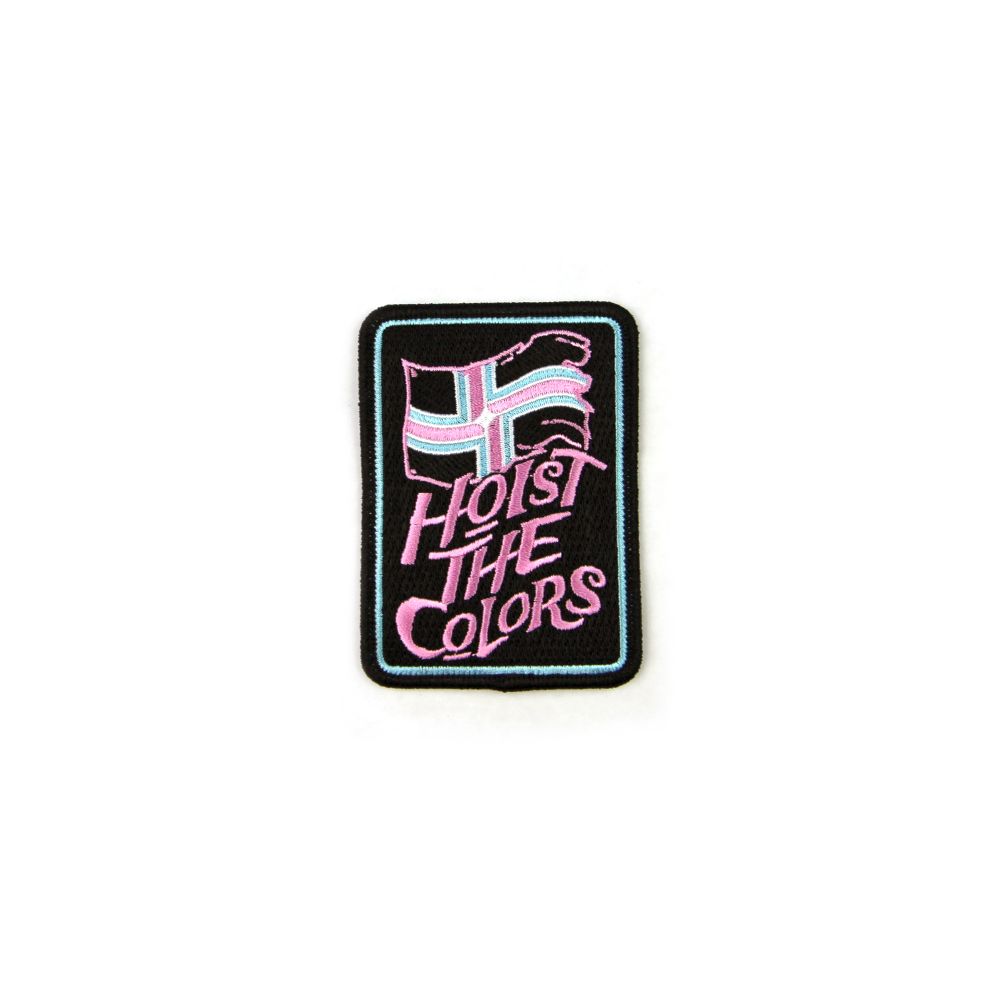 Black patch on a white background. Patch has an embroidered city of Portland flag on top with pink and teal colors to call out Trans Pride. The words “Hoist the colors” is in pink under the flag.