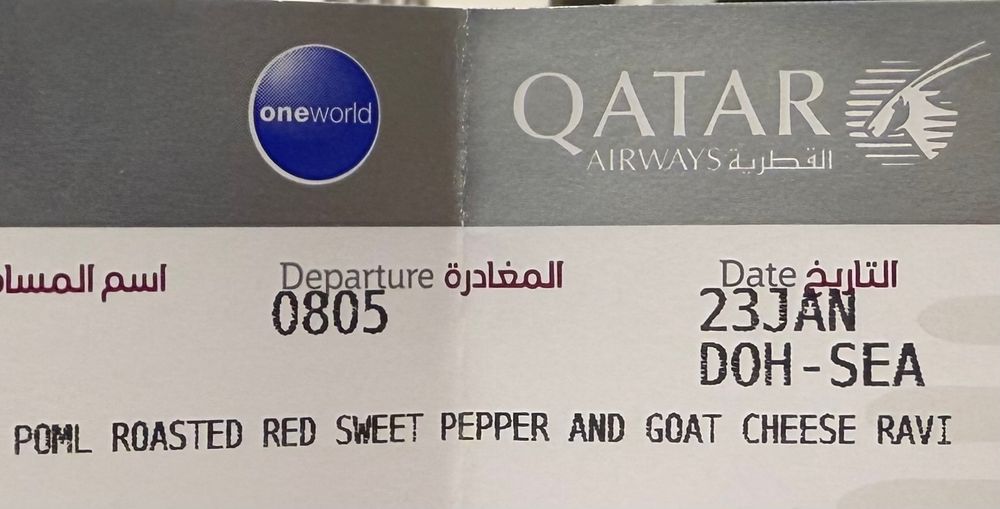 Boarding pass for DOH-SEA with "roasted red sweet pepper and goat cheese ravi" printed on it