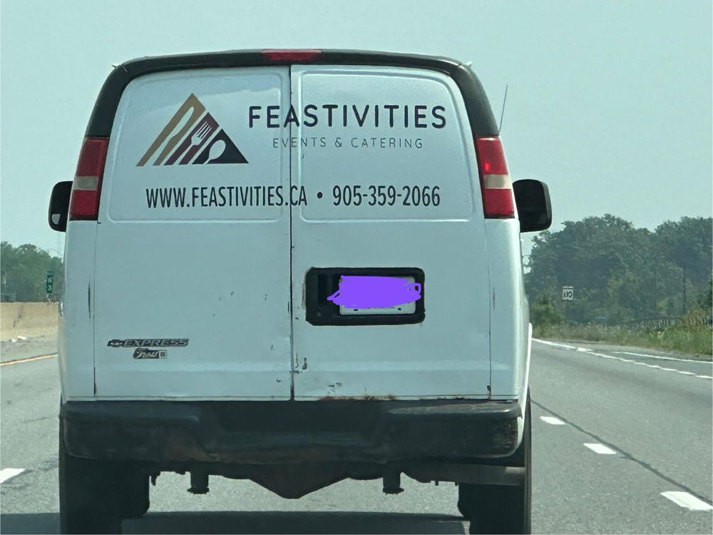 Back of a white van, belonging to a catering company called “Feastivities”. Their triangular logo looks remarkably similar to that of the American Association for Artificial Intelligence. Instead of the three As, however, this caterer’s logo contains a knife, fork, and spoon.