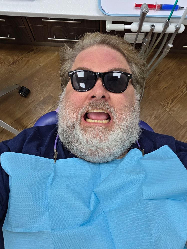 In dentist's chair with bib and dark glasses, awaiting a filling 