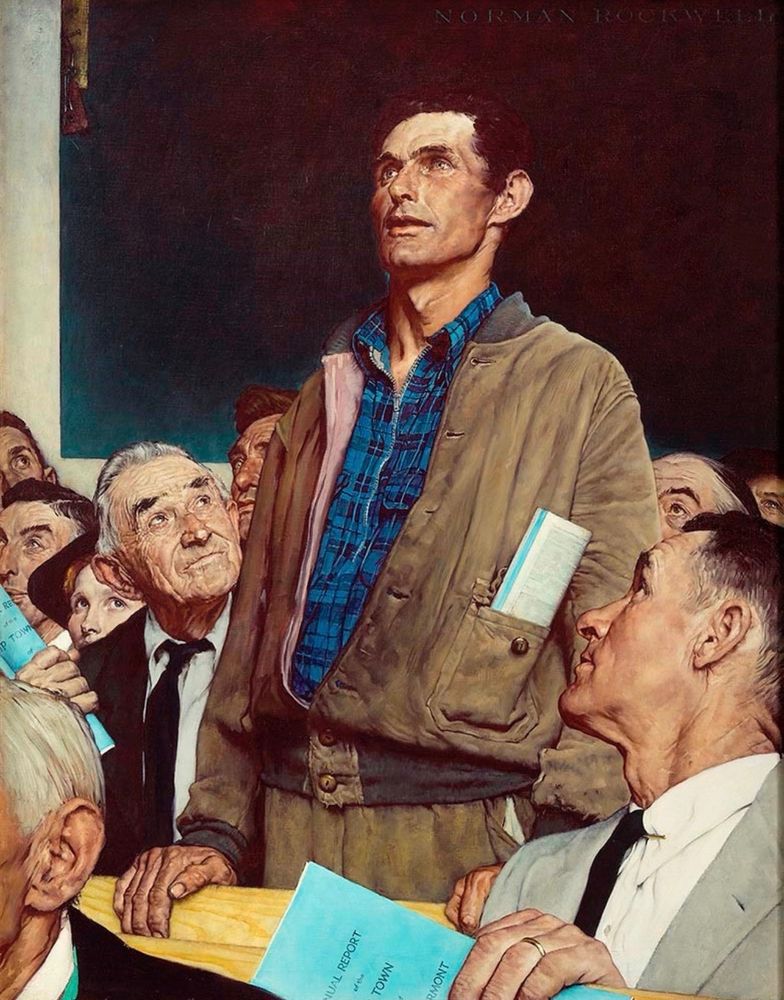 Iconic image of man in brown jacket standing up at a town meeting.