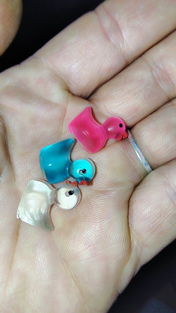 3 small plastic ducks. One is white, one is blue and one is pink. 