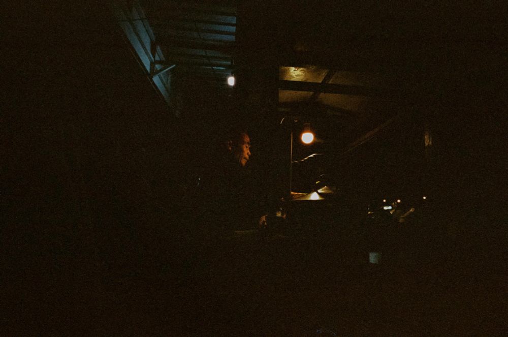 a man in the dark serving bandrek, a ginger beverage 
