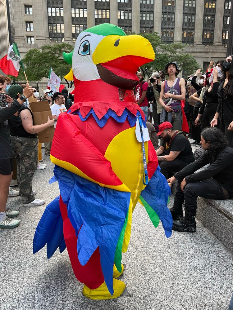 A person in a parrot costume at a protest 