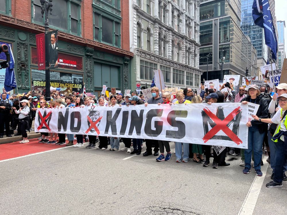 Protesters carry a banner that says “No Kings!”