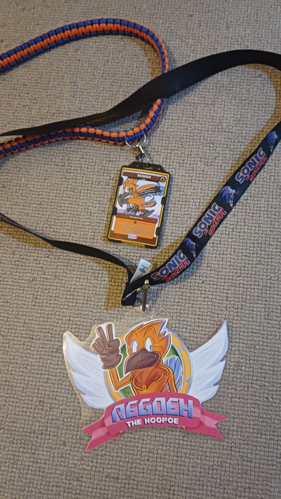 Two lanyards, one with a sonic styled version of a orange and blue Hoopoe bird in the classic sonic ring with wings. And a "trading card" version of the same character in a card holder of  the other. 
