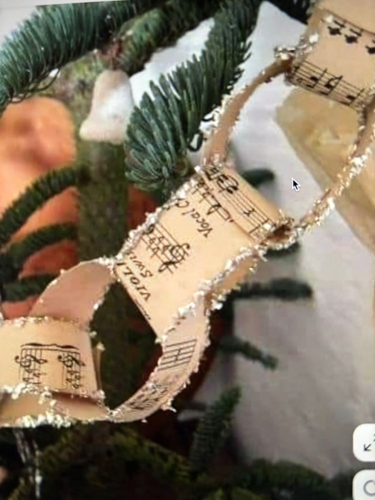 Paper chain made of sheet music with hand-glittered ends strung around a tree