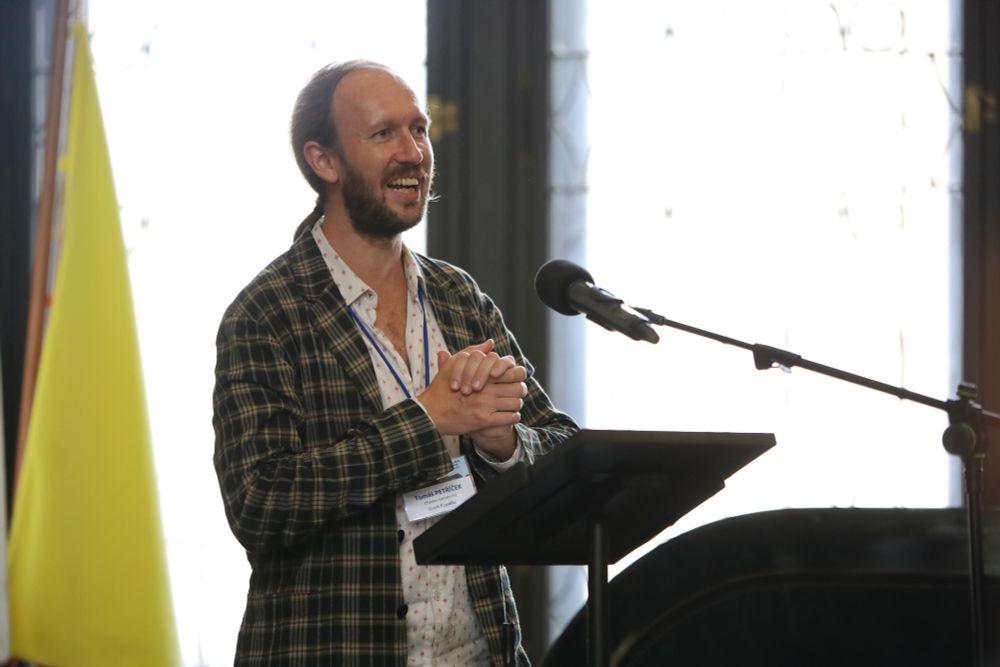 A photo of general chair Tomas Petricek giving a speech at the <Programming> 2025 welcome reception in the old townhall of Prague.