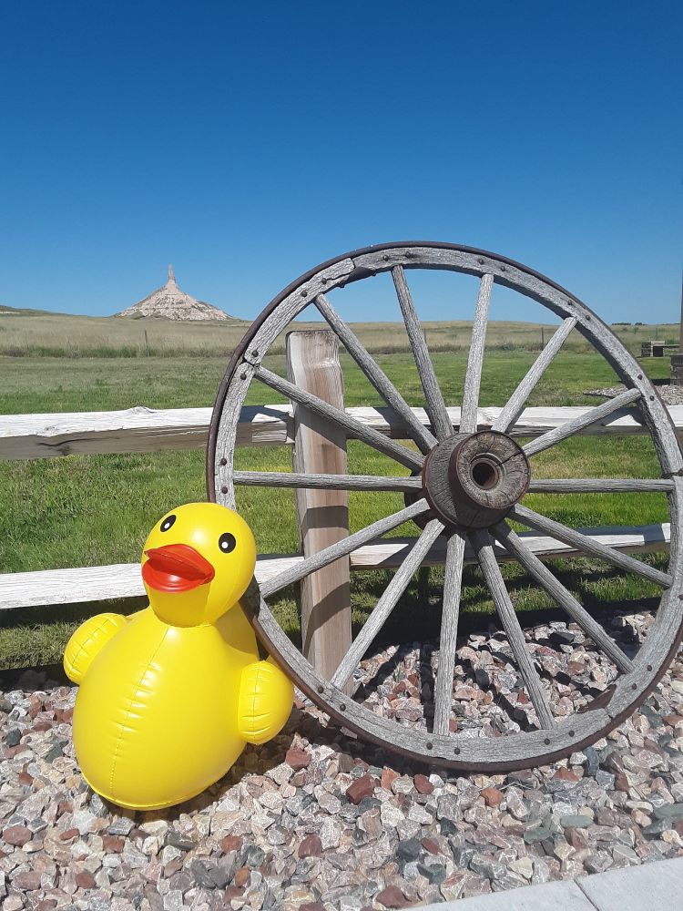 A clear blue sky over Chimney Rock in the distance. In the foreground, a 2 foot inflatable duck is propped up against a wagon wheel and wooden corral fence.

Immediately after taking this photo, I grabbed the duck by the beak and made a mad dash to my car, Philip bouncing against my thigh. I am absolutely certain I looked ridiculous, and it is one of my most favorite memories.