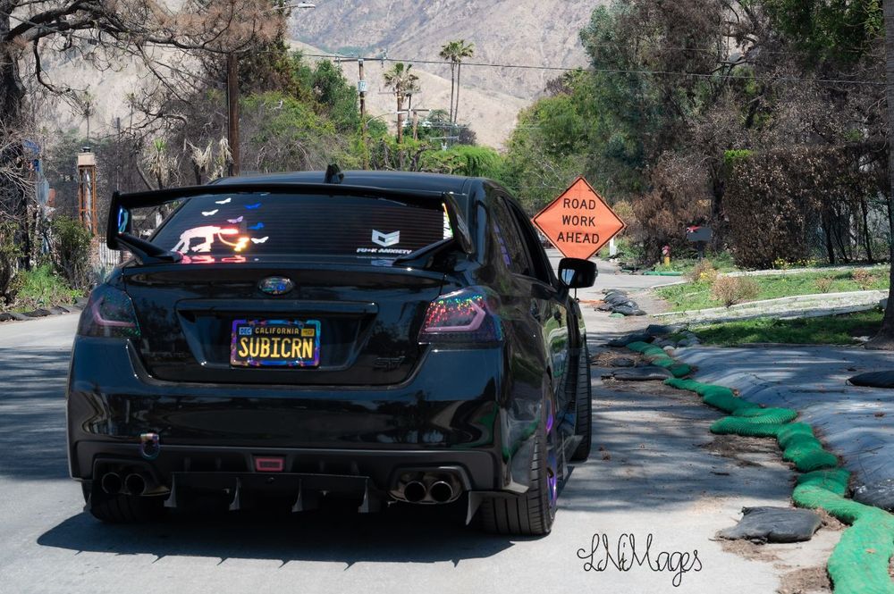 Image of a Subaru WRX STI on side of road in front of a road work sign 