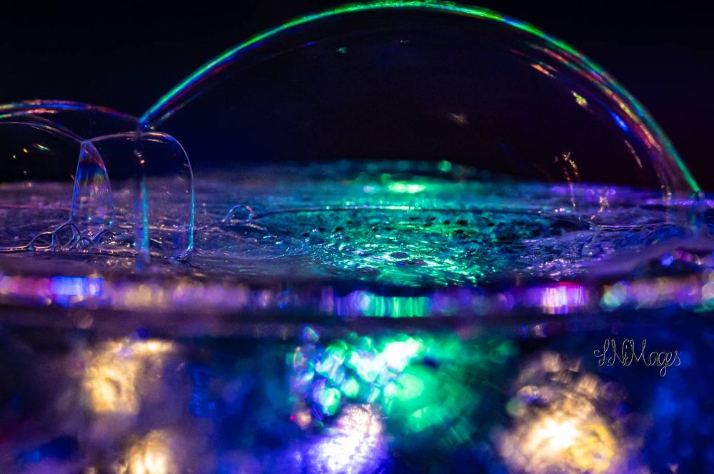 Macro image of bubbles on top of a bowl with lights flashing on the background in all colors
