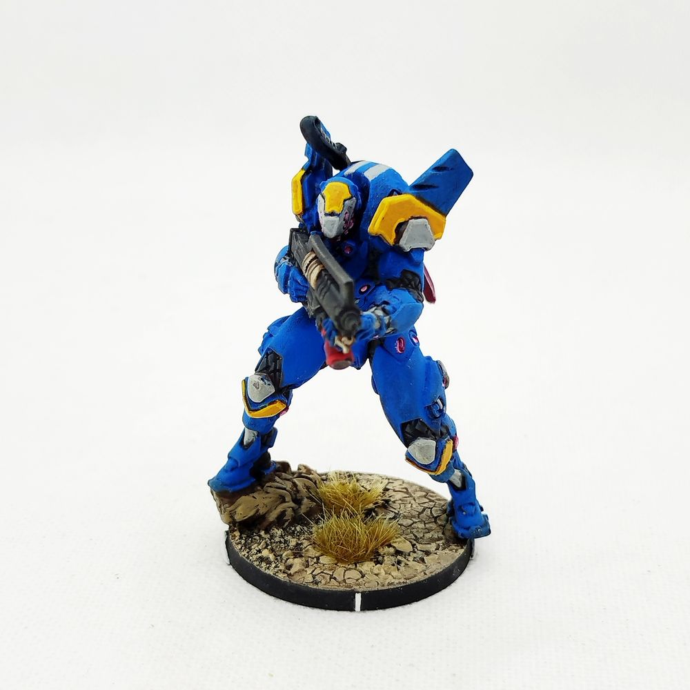 Foto de la miniatura de un Tikbalang Armored Chasseur sobre un fondo blanco.

Se trata de una enorme armadura de combate de color azul con acentos en amarillo y gris. Luces de neón rosa emanan de la armadura.

El casco tiene forma picuda y varias luces en este simulan la forma de una sonrisa despiadada.

Va armado con un arma híbrida de ametralladora y lanzallamas y una espada de energía la cual tiene almacenada en la espalda y cuyo filo brilla también de rosa neón.