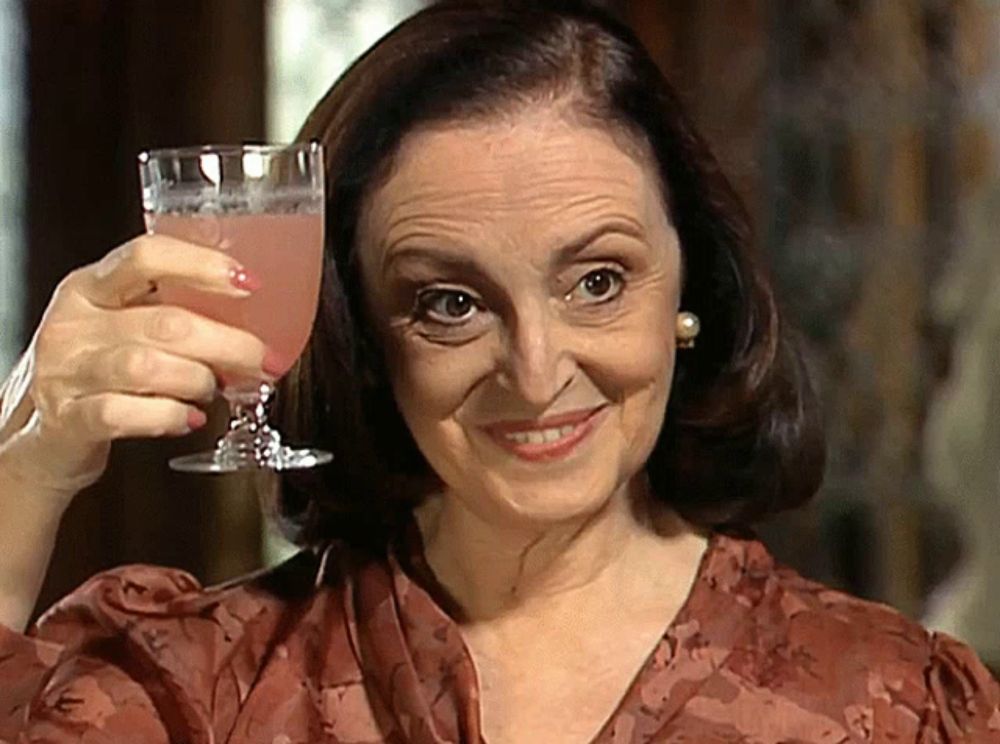 a woman holds up a glass of pink liquid in her hand