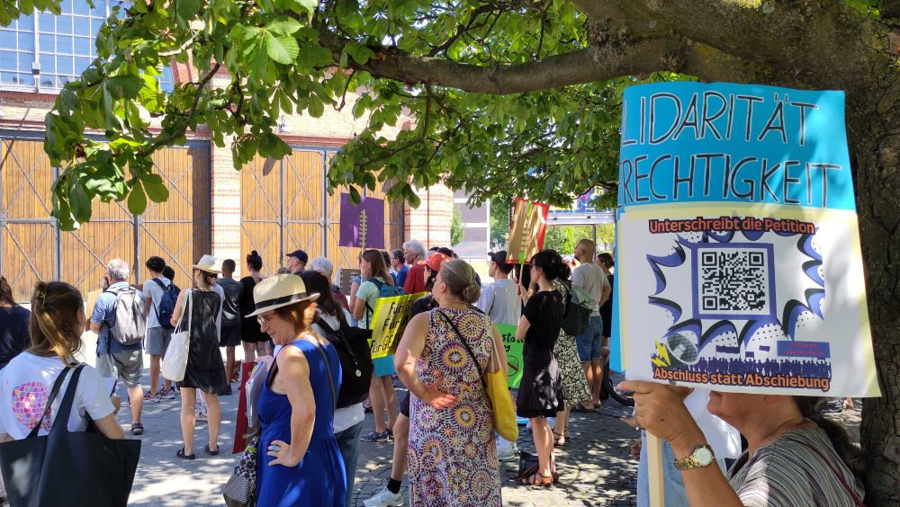 Teilnehmer:innen, Schild "Solidarität und Gerechtigkeit".