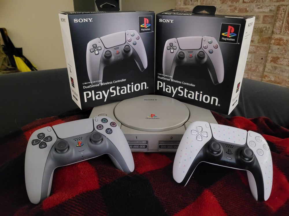 Playstation 30th anniversary PS5 controllers and a Play Has No Limits PS5 controller, displayed in front of a Playstation 1 console.