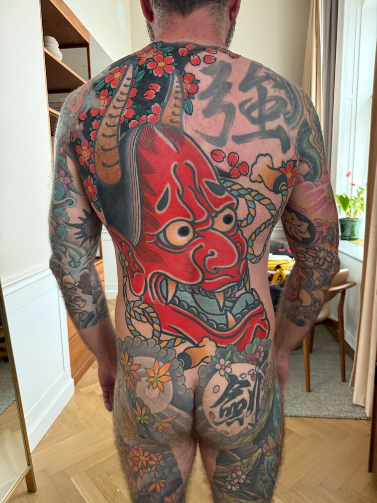 Man with large Japanese suit tattoo across back, buttocks, arms and legs. 