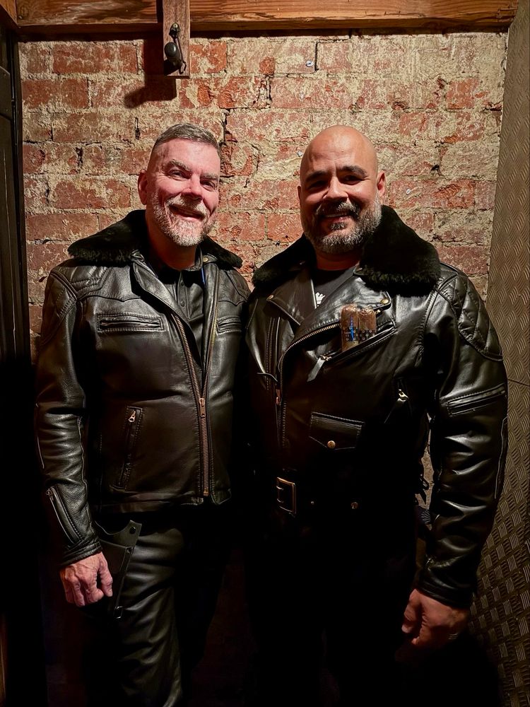 Two men wearing fur collared leather jackets and pants. 