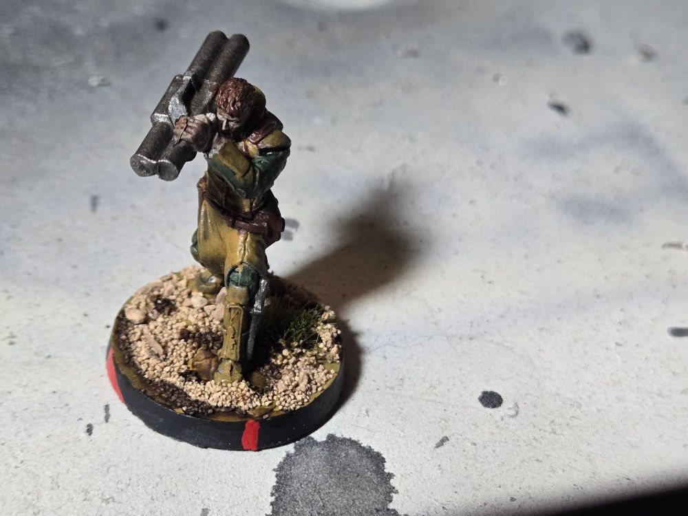 A brown haired male Daylami holding a Panzerfaust over his right shoulder and aiming it with both hands. He has light brown armor and green fatigues.