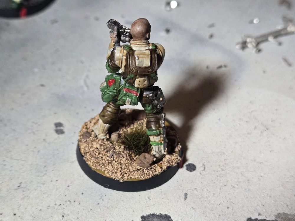Back of Ghulam doctor. Dark brown and tan backpack, green pouches with white and red accents.