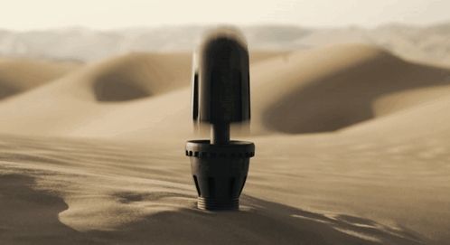 a black object is in the middle of a sandy desert