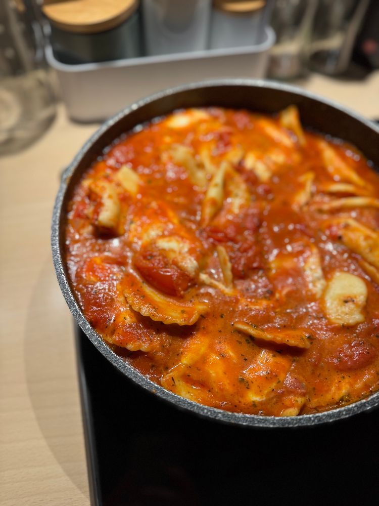 Nahaufnahme einer Pfanne auf einem Herd mit Zitronen-Ricotta-Cappelletti in Tomaten-Mozzarella-Soße