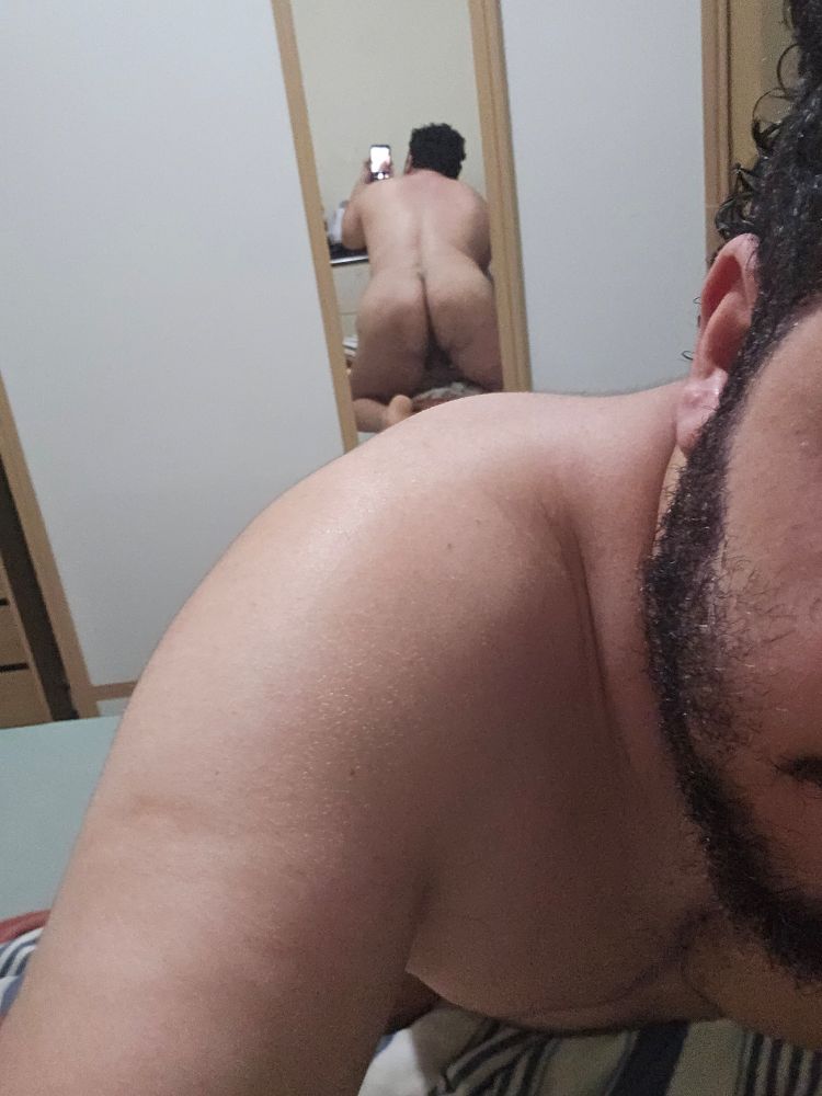 Homem pelado de costas para espelho de um guarda roupas. Ao fundo mostra reflexo das costas e bunda