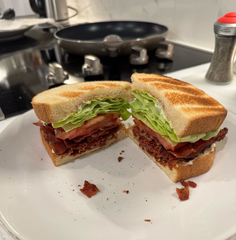 Another BLT sandwich, sliced in half, presented on a plate. 