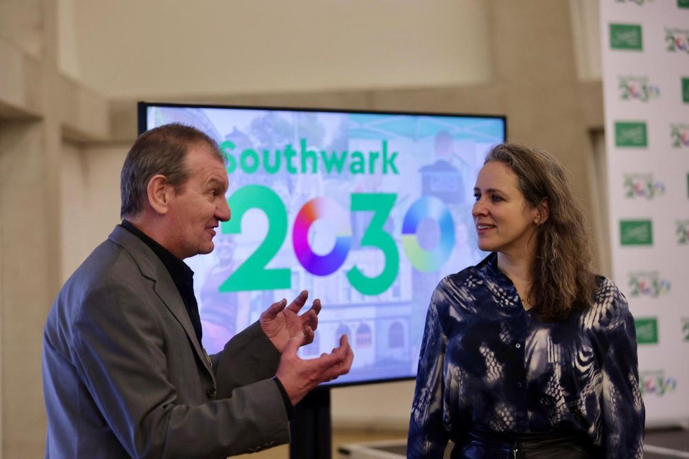 An image of Sarah smiling speaking to a man in front of a screen reading 'Southwark 20230'