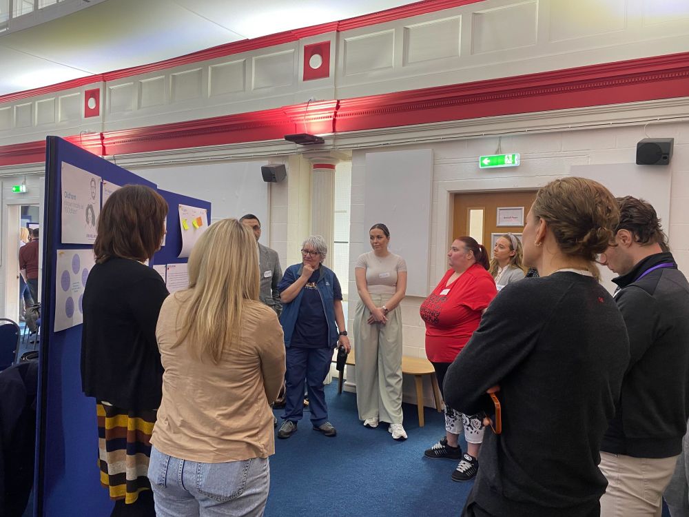A group of people stood around a board discussing.