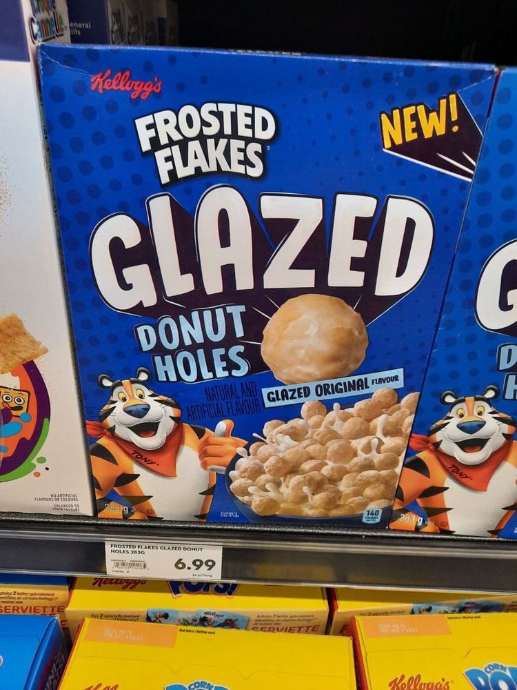 A box of Kellogg's Frosted Flakes Glazed Donut Holes with the wird Glazed larger than anything else, featuring Tony the Tiger in the lower left corner and a huge glazed donut hole near the middle above a bowl of the cereal in milk in the lower right.