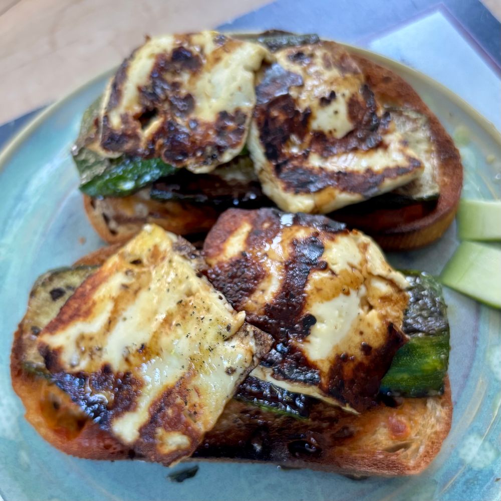 Two slices of jalapeño cheese bread sit on a plate heaped with grilled slices of zucchini and halloumi cheese. It doesn’t look like much but it tasted wonderful!