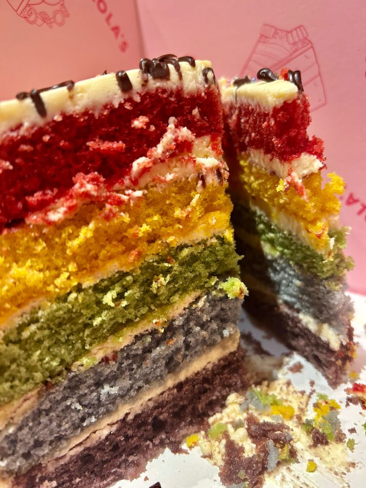 Cross-section of a rainbow birthday cake, all seven colours with white buttercream between, icing on top, saatranga as my helpful family say