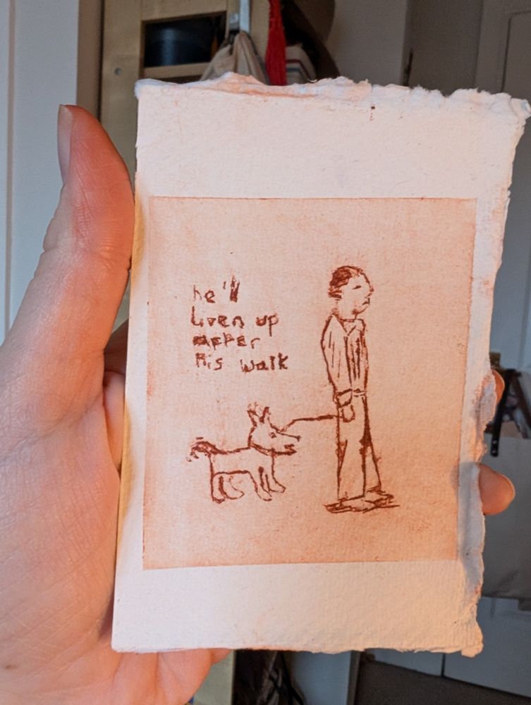 A hand holding a print of a happy dog on a lead behind a tired/I energetic man. The caption says "he'll liven up after his walk" and is from the dog's point of view about the man. The print is brown.