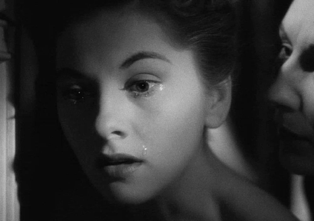 a black and white photo of a woman with tears running down her face