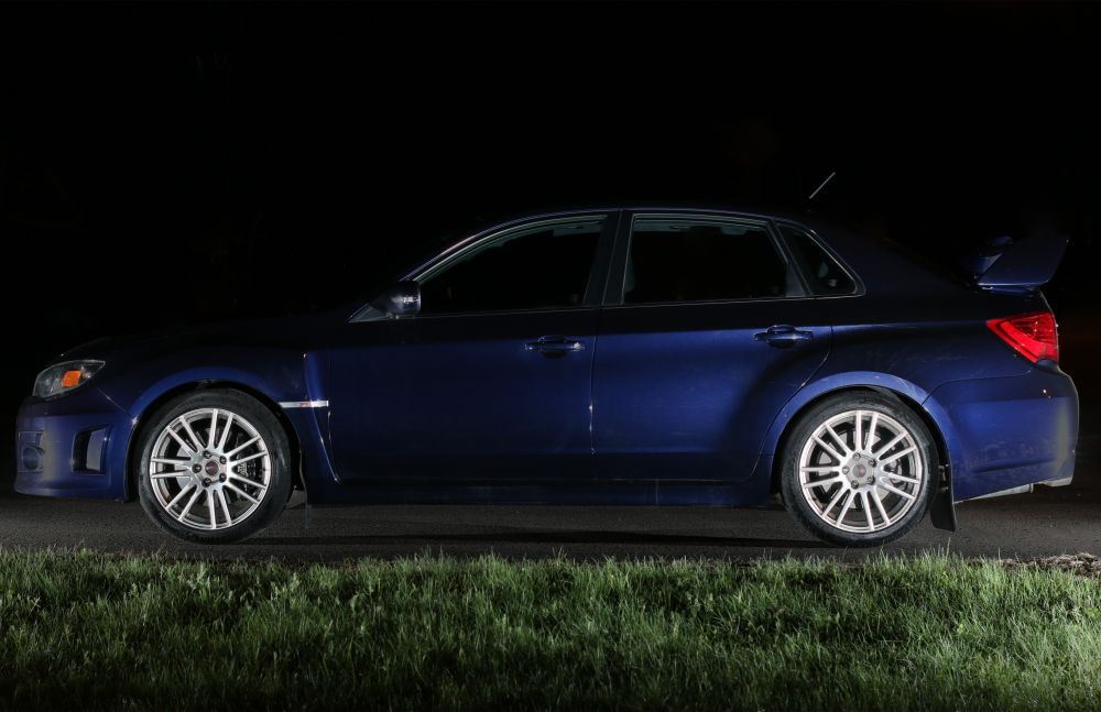 Dark blue 2011 WRX STi viewed from the side at night