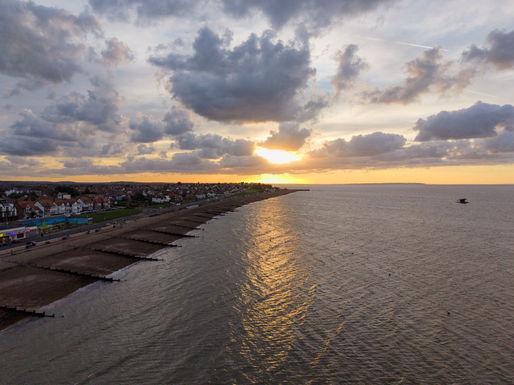 A drone photo of the sun setting over the Herne Bay seafront, with the sunlight glinting off the water.