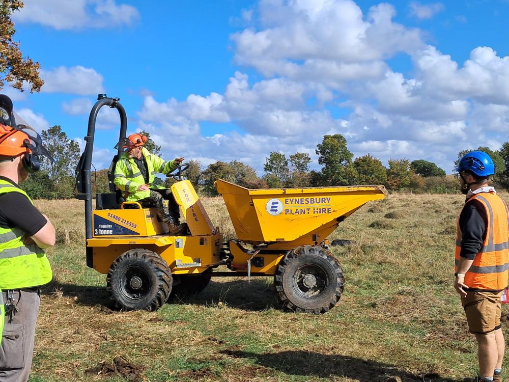 Adam is learning to drive a dumper truck, looking behind as he reverses