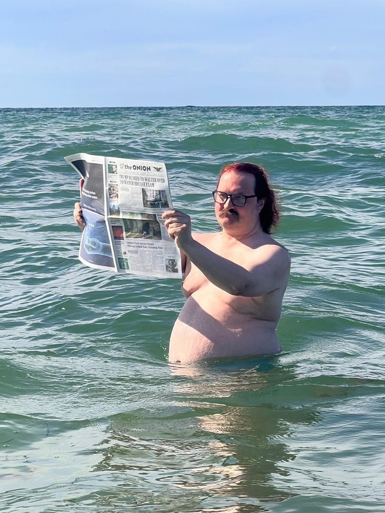 Peter in the ocean, reading The Onion newspaper