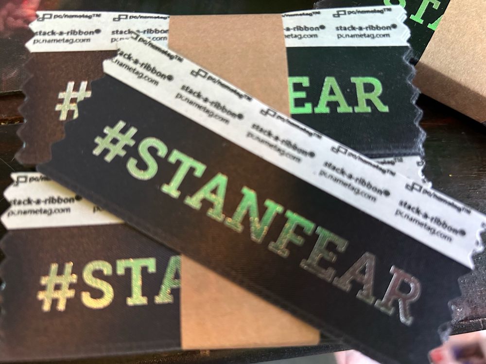 A black badge ribbon with “#STANFEAR” written in silver letters.