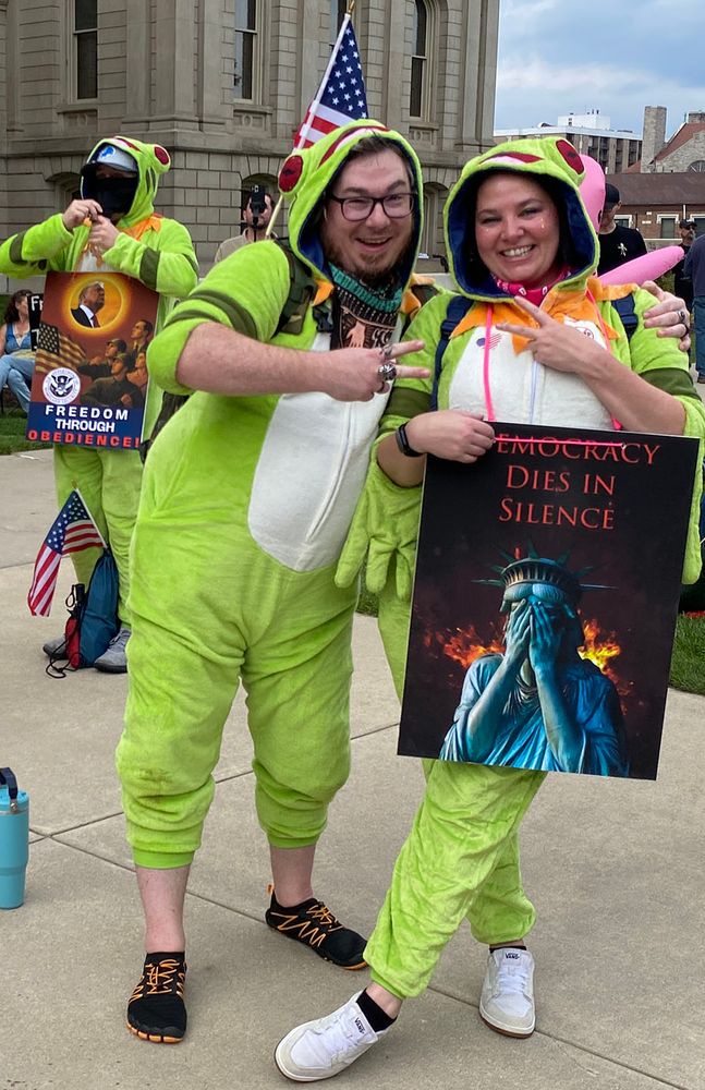two protestors in frog costumes giving peace signs
